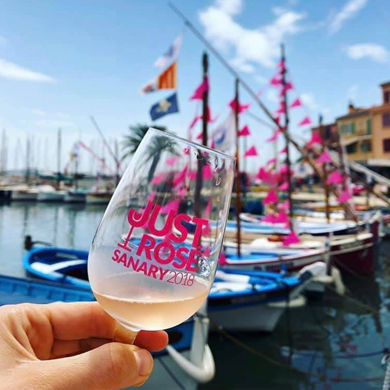 Verre de vin rosé devant le port de Sanary-sur-Mer du Festival International Just'Rosé avec des créations graphiques et logos réalisés par yo design, Yunaima Oyola.