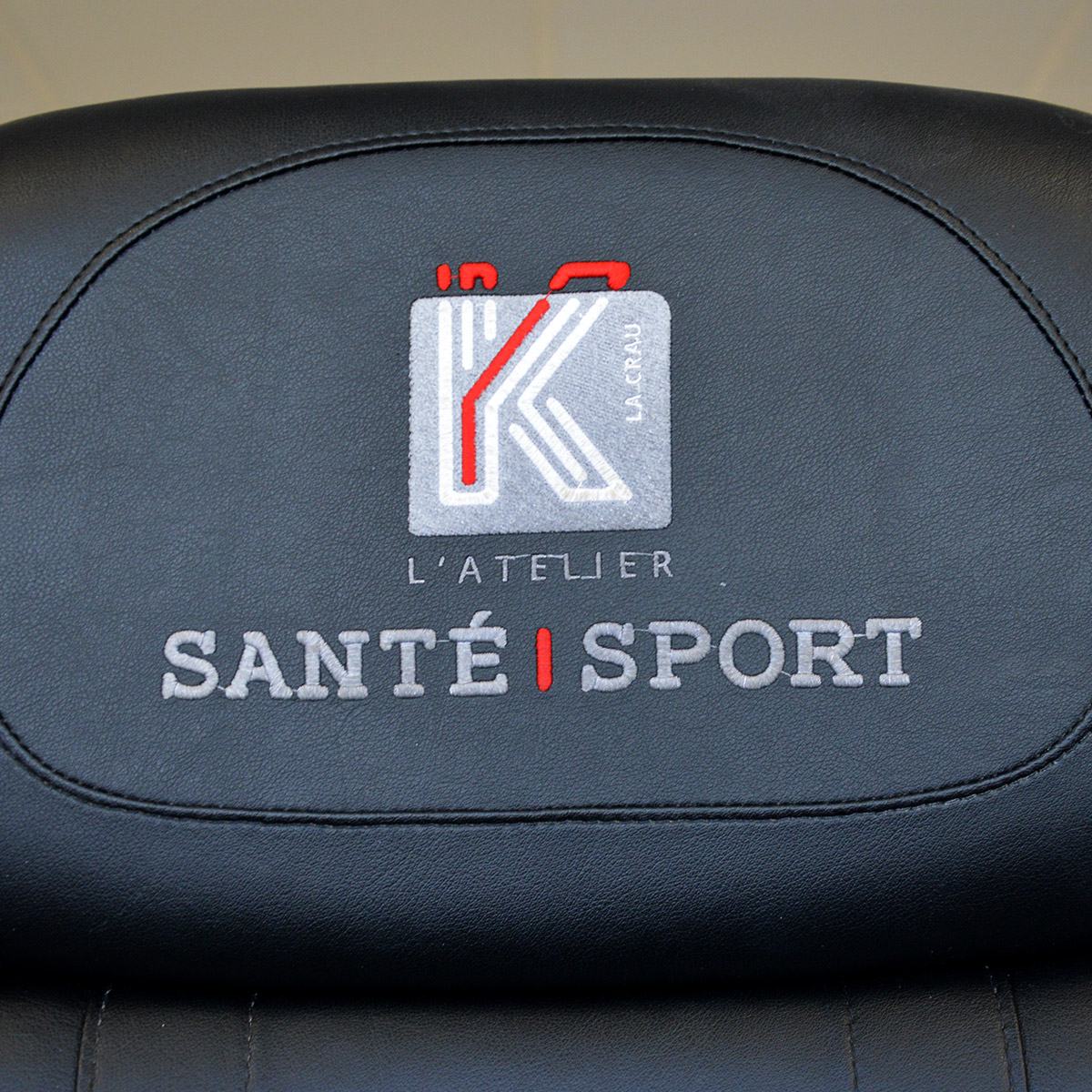 Broderie sur fauteuil contenant le logo bleu et orange aux formes arrondies et modernes pour K Santé Sport, cabinet de kinésithérapie situé à La Crau dans le Var, créé par Yunaima Oyola, Yo Design, graphiste et web-designer basée à Cherbourg-en-Cotentin